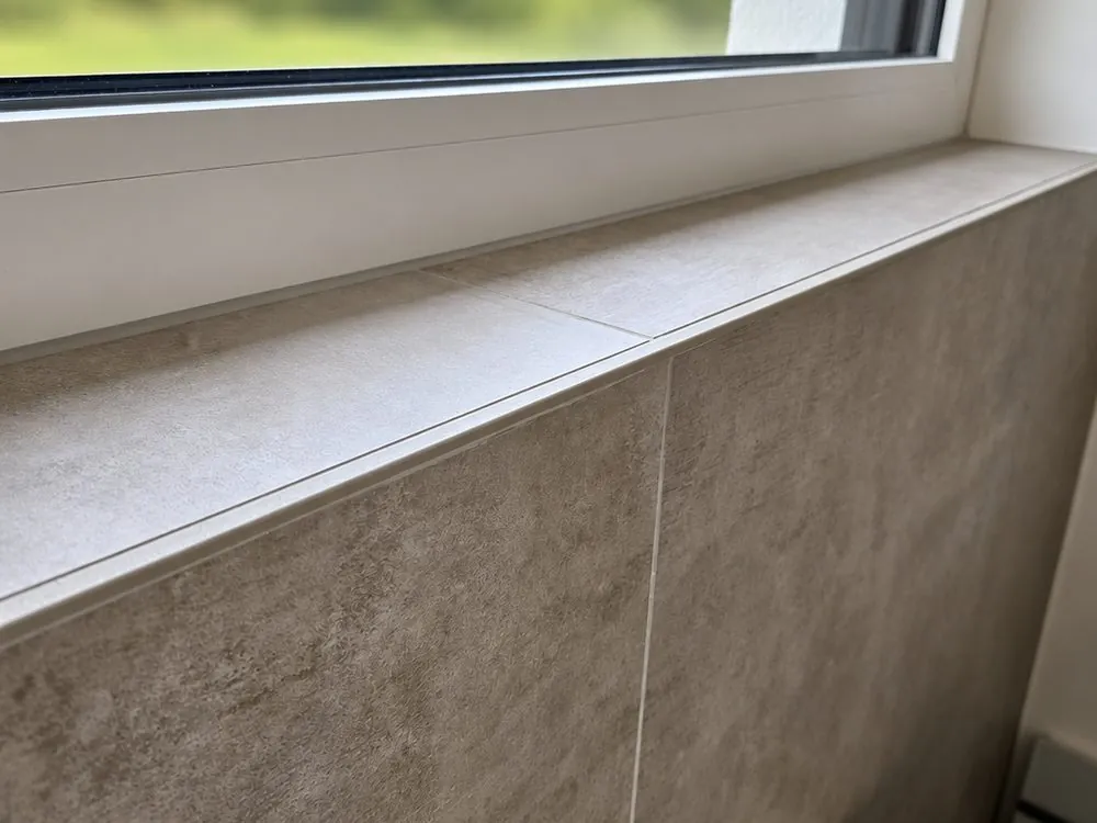 Detail: Fensterbank mit derselben Fliese belegt, feine Fugen und saubere Kante